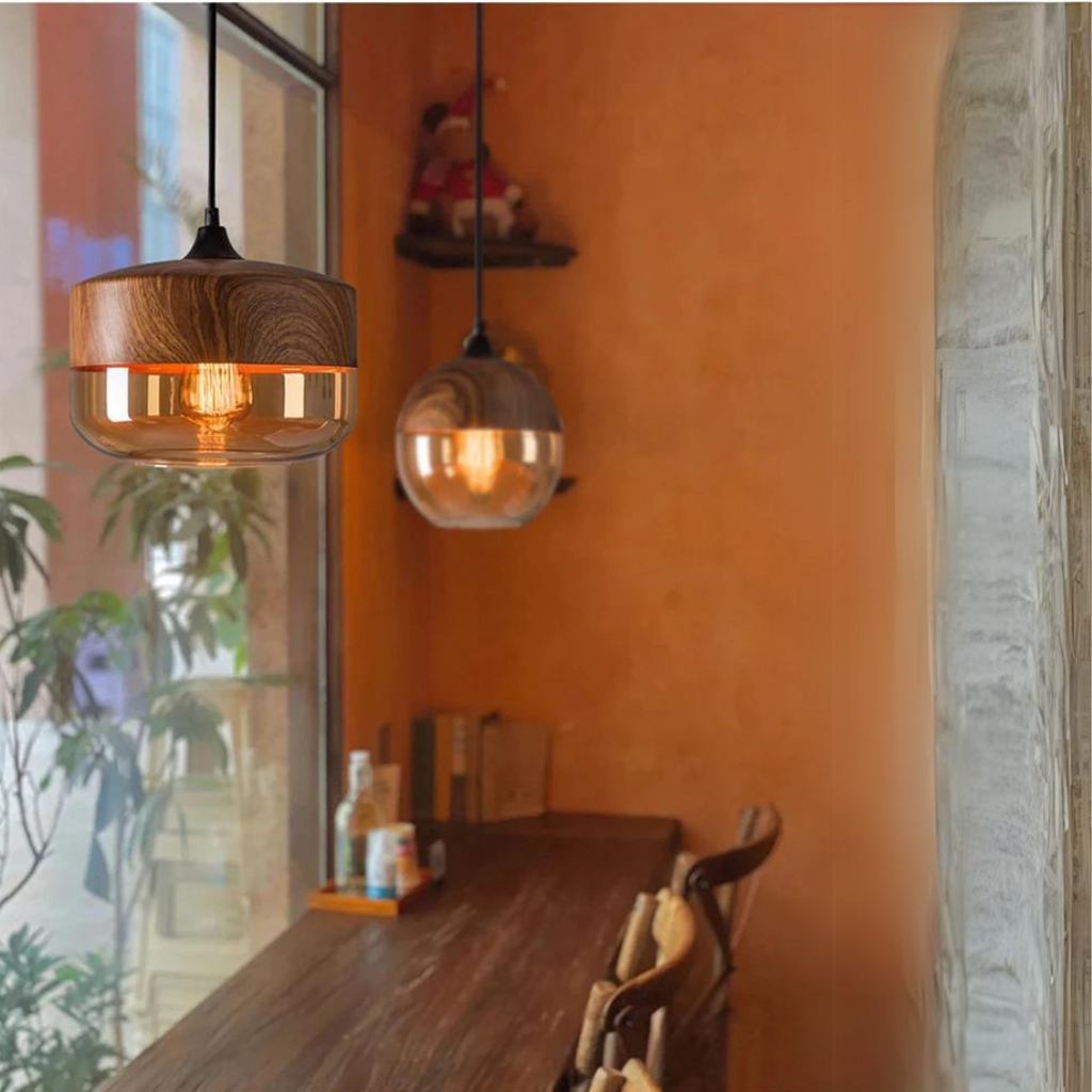 Glass pendant light pair hanging beside an orange wall