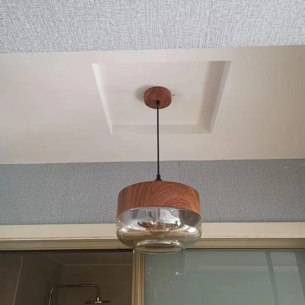 Wide glass pendant light installed from a ceiling canopy in a room