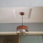 Wide glass pendant light installed from a ceiling canopy in a room