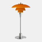 Amber glass table lamp with a silver finish base on a plain background