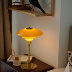 Amber glass table lamp with a gold finish beside framed wall art