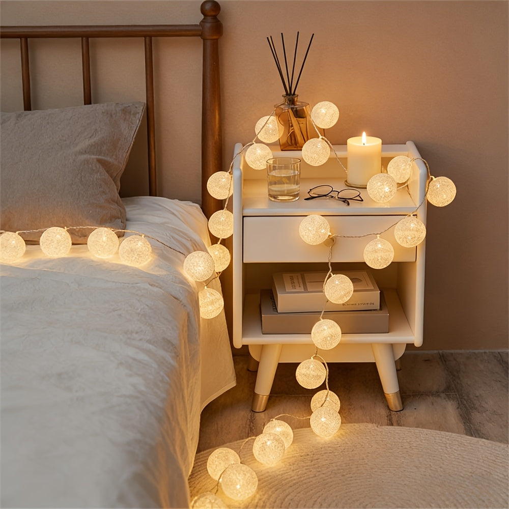 Globe fairy lights draped around a bedside table beside a bed.