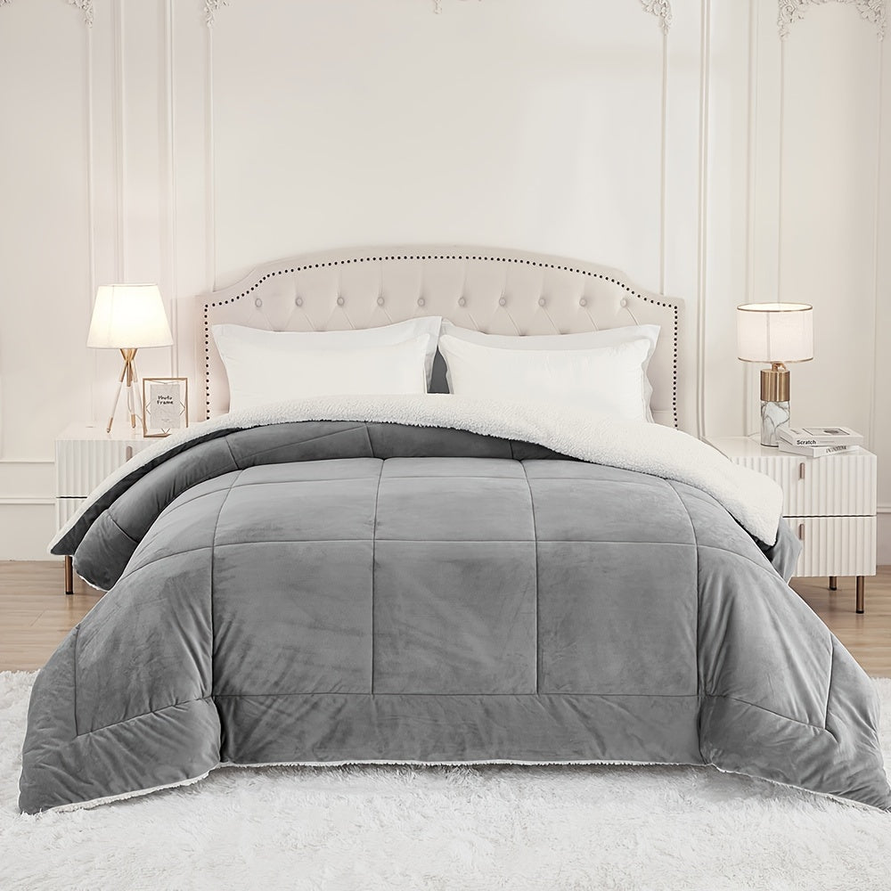 Gray box quilted plush comforter with white fleece reverse on a bed