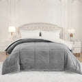 Gray box quilted plush comforter with white fleece reverse on a bed