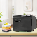 Black 8L towel warmer cabinet on a countertop beside folded towels