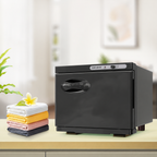Black 8L towel warmer cabinet on a countertop beside folded towels