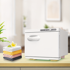 White 8L towel warmer cabinet on a countertop beside folded towels