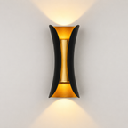 Black and gold outdoor wall sconce mounted on a light wall, casting warm light upward and downward.