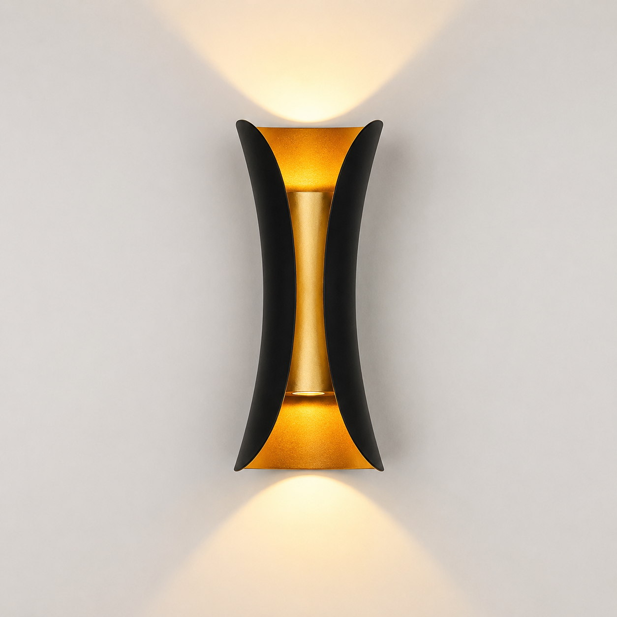 Black and gold outdoor wall sconce mounted on a light wall, casting warm light upward and downward.