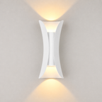 White outdoor wall sconce mounted on a light wall, casting warm light upward and downward.