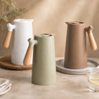 Pearl white, moss green and chestnut brown insulated carafes stand together.