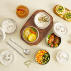 Insulated lunch box shown as several open white containers with lids and cutlery.
