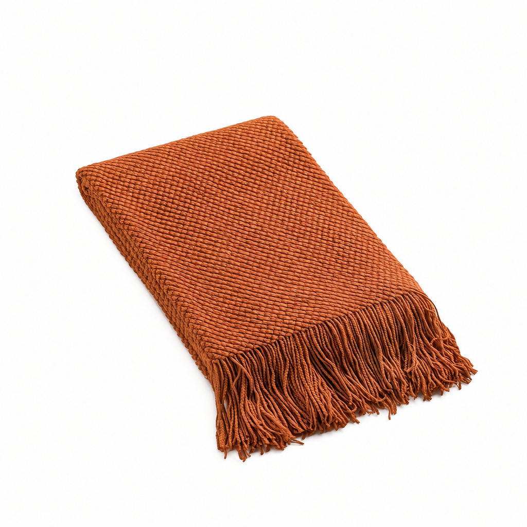 Folded burnt orange knit throw blanket isolated on a white background
