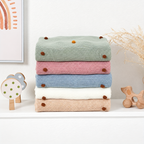 Folded acrylic knit throw blankets showing colorful dot accents in the source color range