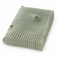 Folded light green acrylic knit throw blanket with colored dots on a white background