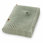 Folded light green acrylic knit throw blanket with colored dots on a white background