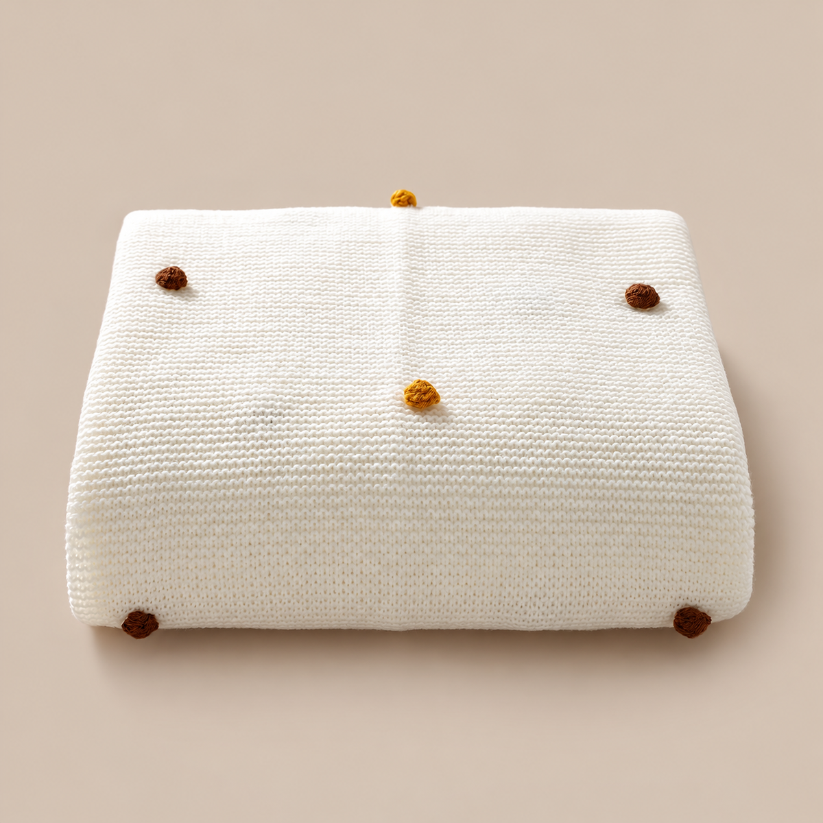 Folded white acrylic knit throw blanket showing colored pom pom dots