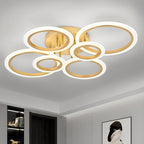 Gold six ring LED ceiling light illuminating a modern room.