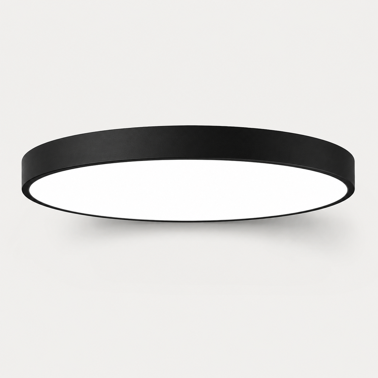 A minimalist circular flush-mount ceiling light with a matte black outer frame and a bright white diffuser, shown against a clean light gray background.