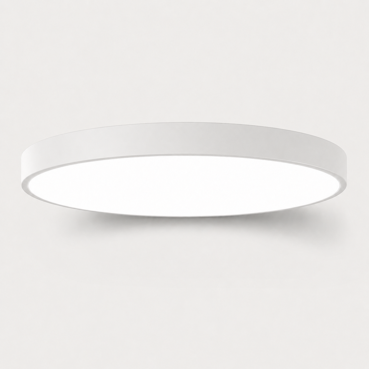 A minimalist, modern circular flush-mount ceiling light in white, shown against a clean, light gray background.