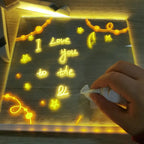 Hand wiping a handwritten message from the illuminated acrylic board