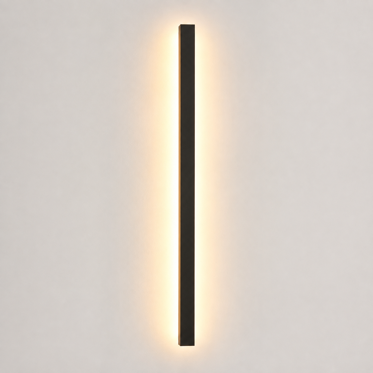 Slim black wall sconce glowing warm white against a light neutral wall.