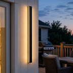 Black wall sconce glowing on an outdoor column beside a patio at dusk.