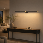 Linear wall sconce providing warm lighting above a long black console table.