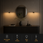 Linear wall sconce casting warm light above a round mirror with feature icons below.