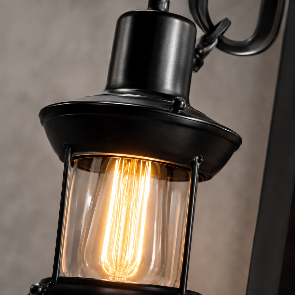 Black lantern wall sconce close-up showing the metal shade and exposed glowing bulb.
