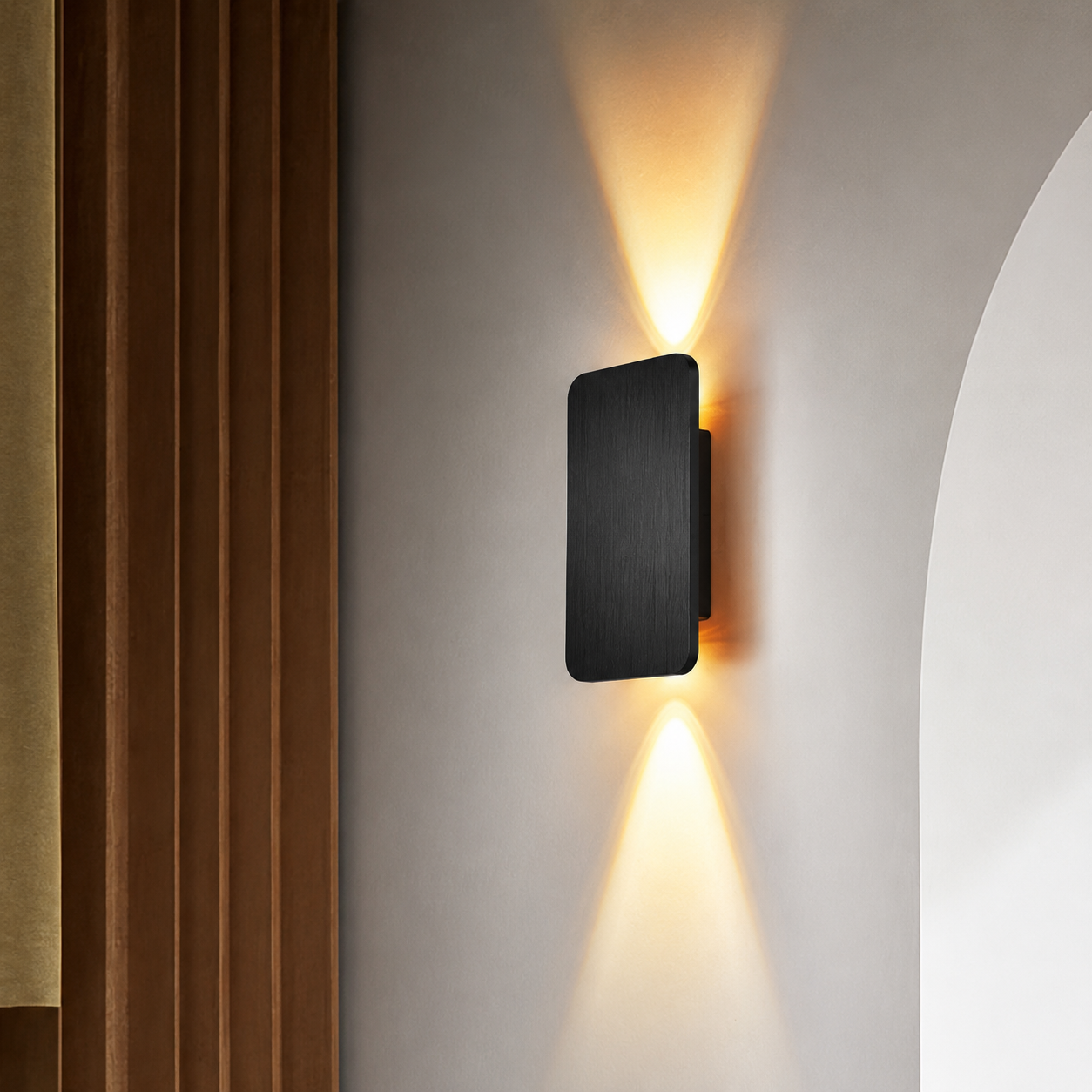 Black rectangular wall sconce casting warm upward and downward light on a neutral wall.