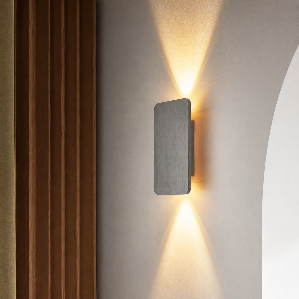 Gray rectangular wall sconce casting warm upward and downward light beside wood panels.