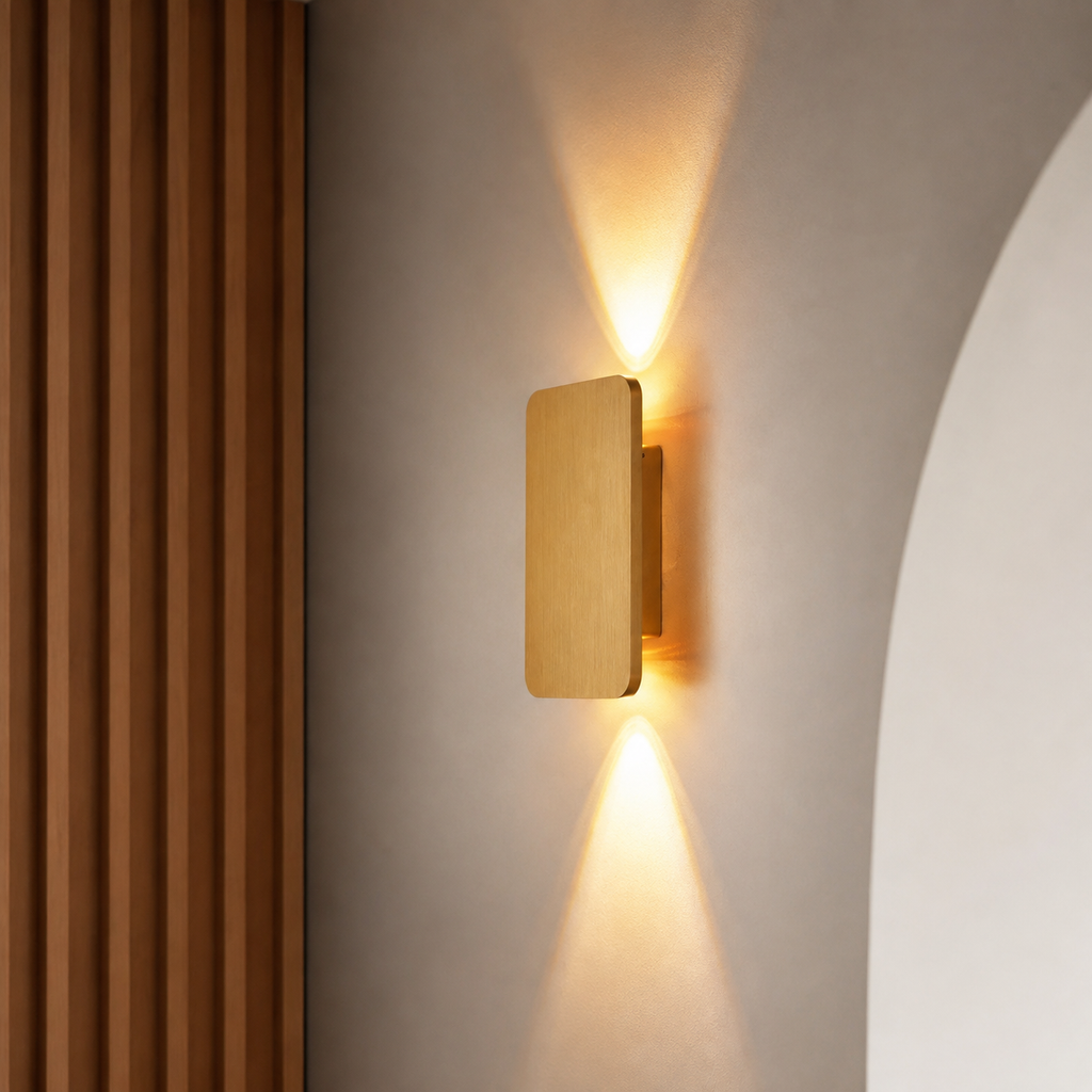 Gold rectangular wall sconce casting warm upward and downward light beside vertical wood panels.