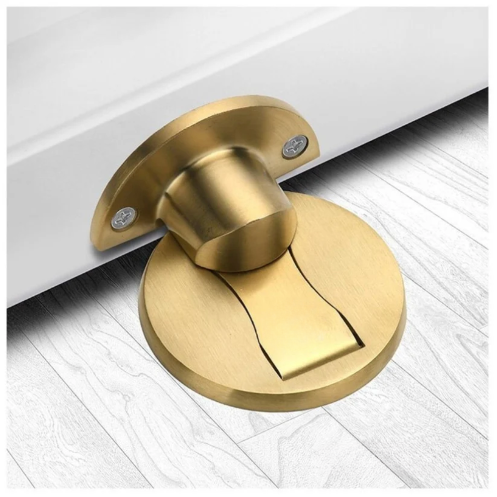 Gold magnetic door stop mounted on a light wood floor.