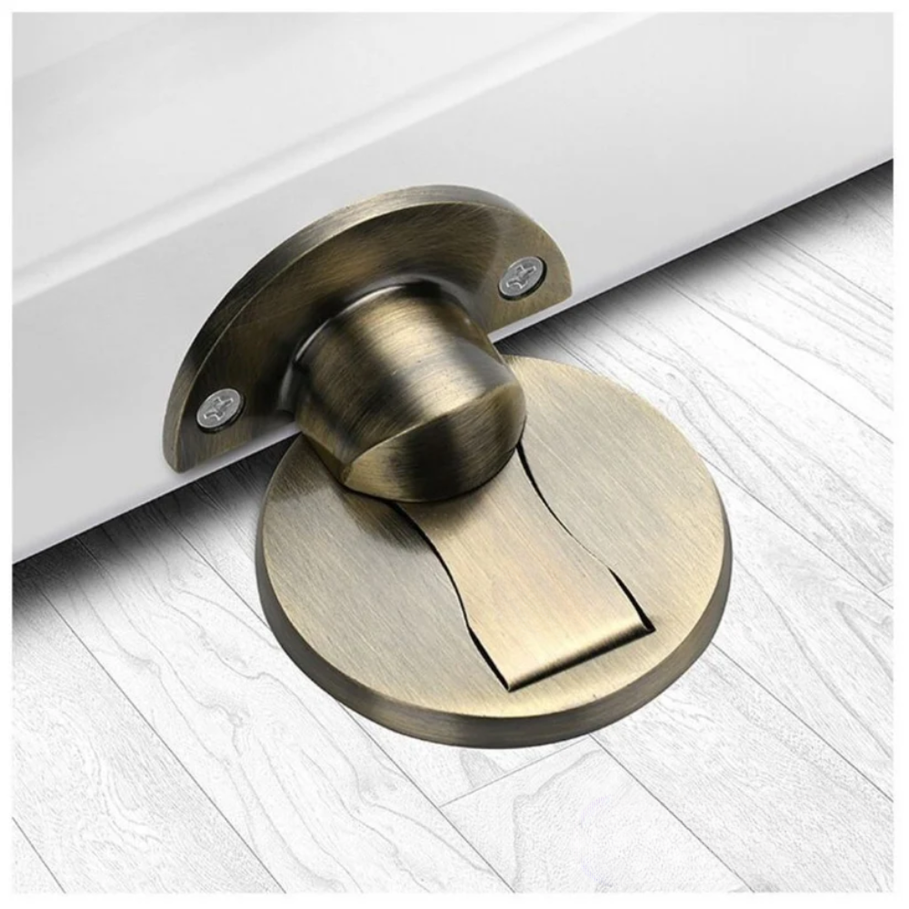 Bronze green magnetic door stop installed beneath a white door.
