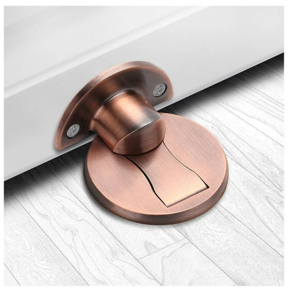 Bronze reddish magnetic door stop mounted on pale flooring.