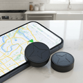 Compact black magnetic GPS tracker beside a smartphone
