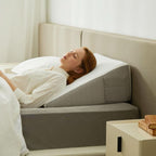 Gray wedge pillow raising the upper body on a bed.