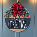Merry Christmas round sign with plaid bow and artificial greenery hanging on a dark blue door