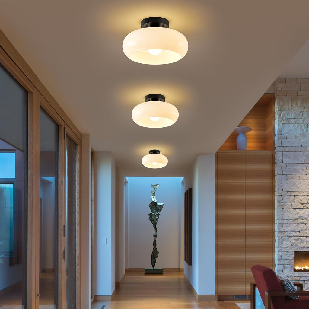 Milk glass ceiling lights with black mounts installed along a hallway.