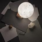 White 3D moon lamp beside books and a ceramic vase