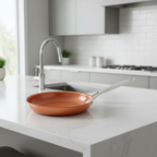 Copper frying pan resting on a white kitchen island.