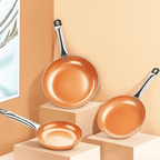 Three copper frying pans in graduated sizes arranged on display blocks.