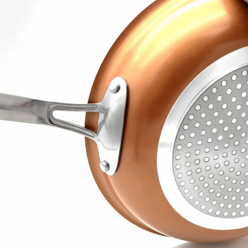 Close-up of the perforated stainless steel induction base and riveted handle.
