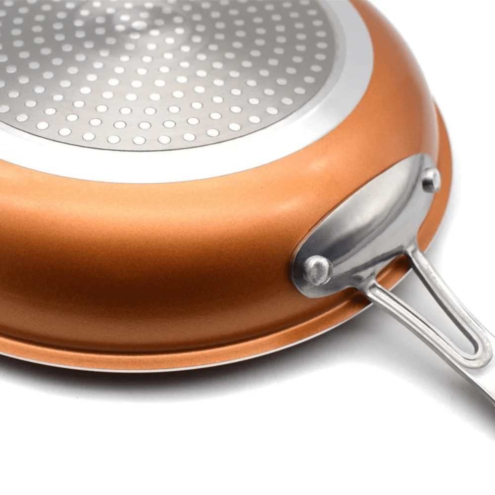 Close-up of a copper pan induction base and riveted stainless steel handle.