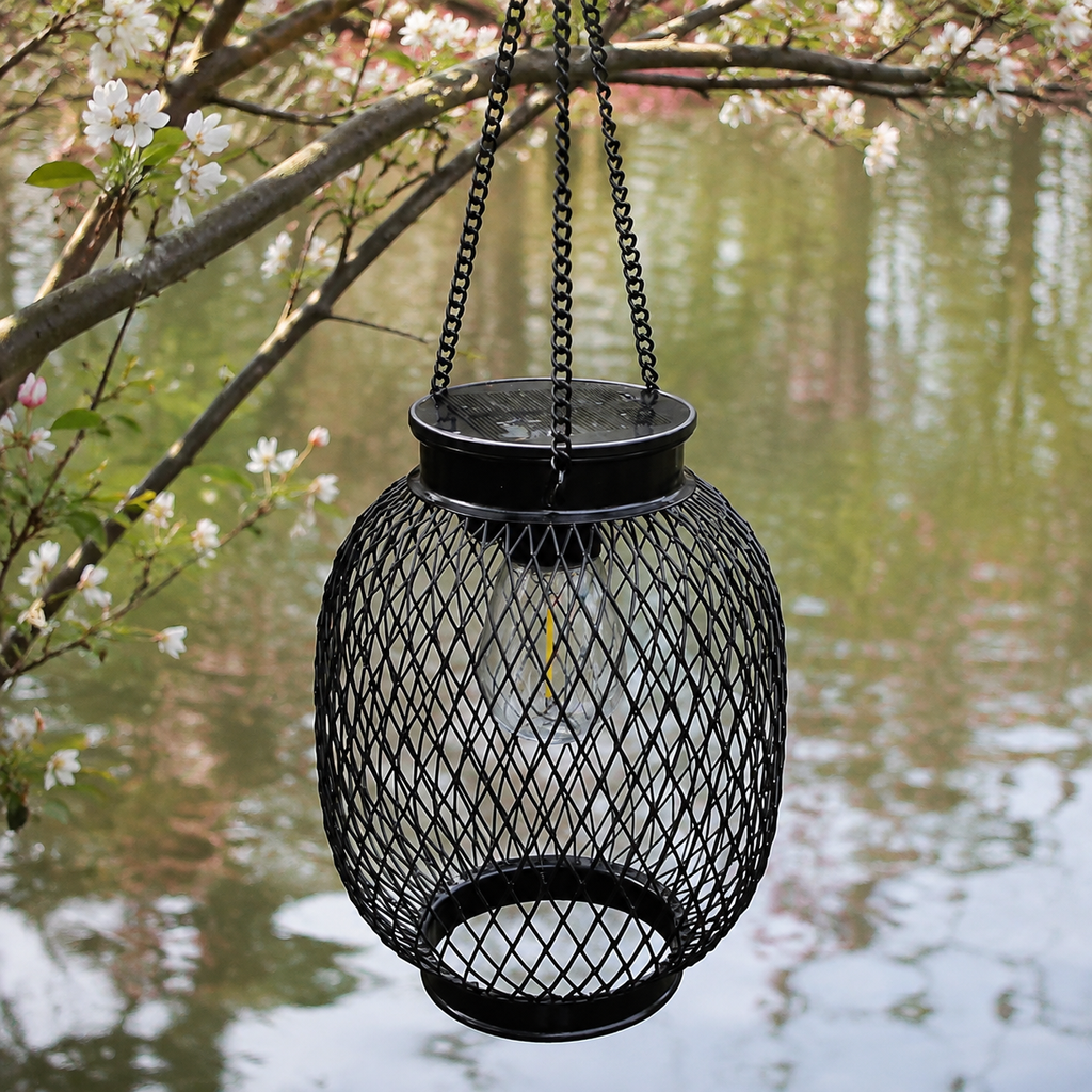 A round outdoor solar lantern hangs unlit above calm water and spring blossoms.