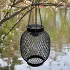A round outdoor solar lantern hangs unlit above calm water and spring blossoms.