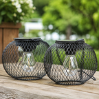 Two unlit outdoor solar lanterns rest on a weathered wood table in daylight.