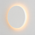 White round outdoor wall light glowing with a warm halo against a plain light background.