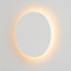 White round outdoor wall light glowing with a warm halo against a plain light background.